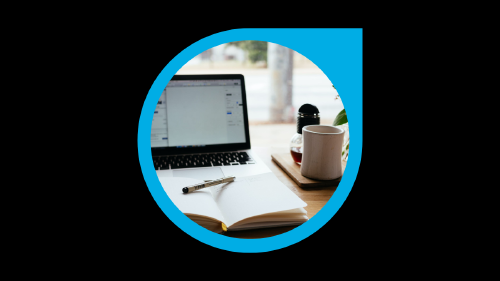 Escritorio con ordenador, una agenda, bolígrafo y una taza de café 
